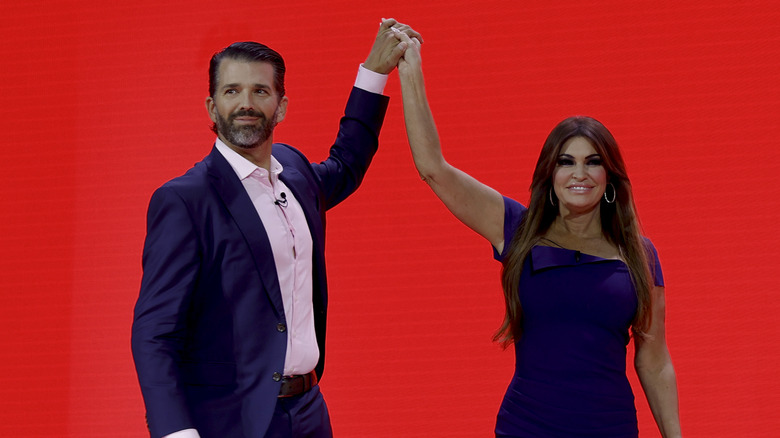 Donald Trump Jr. and Kimberly Guilfoyle hold each other's hands in the air