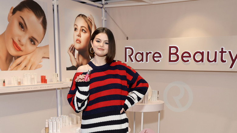 Selena Gomez posing with Rare Beauty product at event 