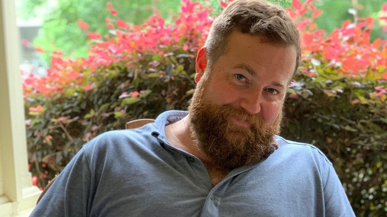 Ben smiles at the camera in front of flowers