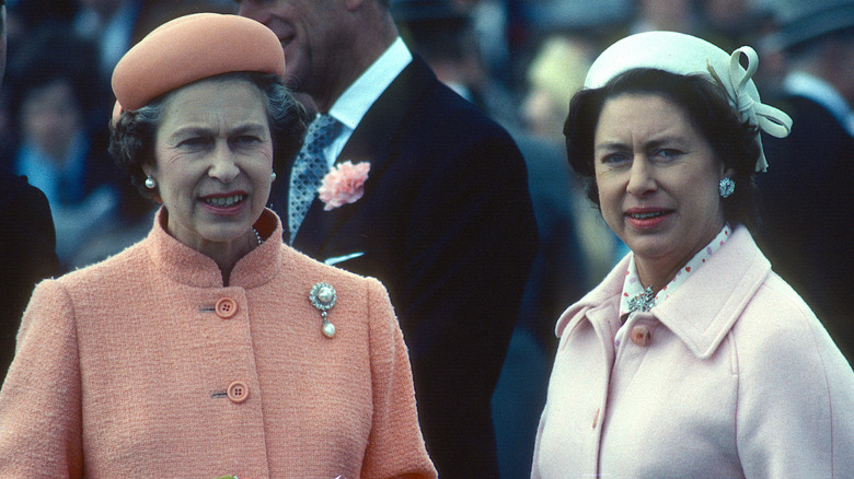 Queen Elizabeth in a tangerine suit and Princess Margaret in a pale pink suit