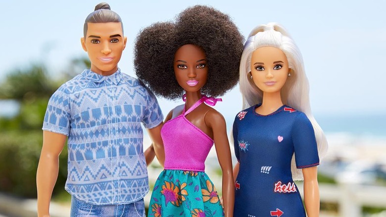 Ken and two Barbies standing together