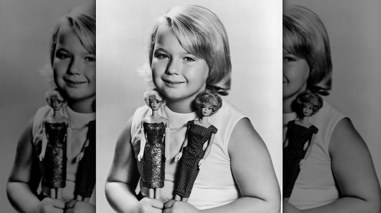 Black and white image of girl holding vintage Barbies