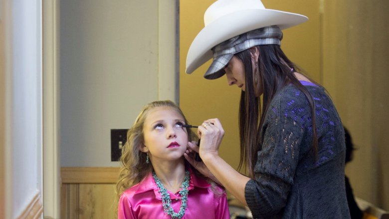 Mom applying makeup to girl