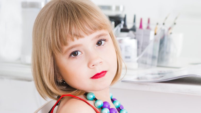 Pensive-looking child wearing lipstick