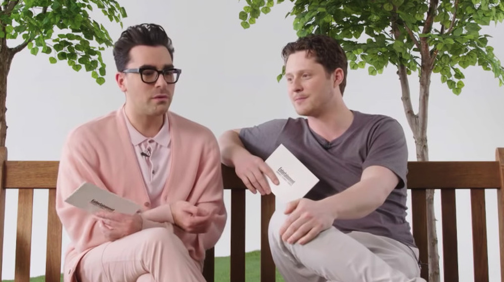Dan Levy and Noah Reid sitting on a bench