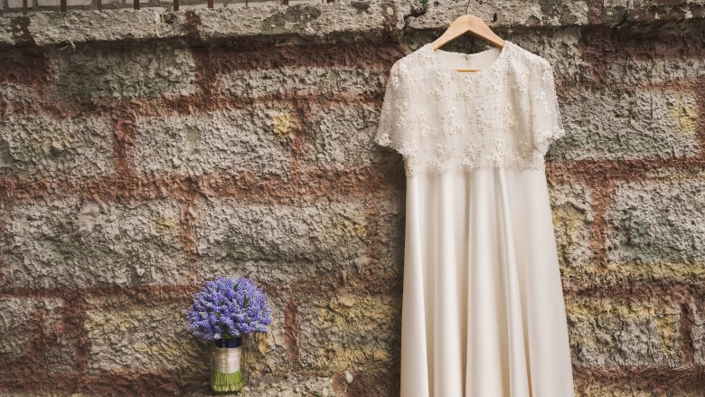 Casual wedding dress hanging against brick wall