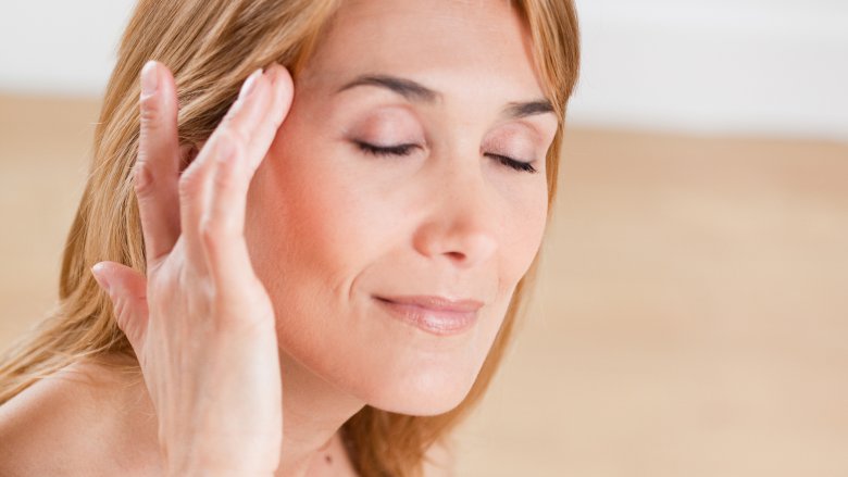 woman applying essential oil to temples