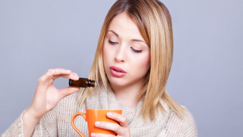 Woman pouring essential oil into beverage