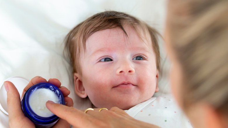 Mother putting cream on baby