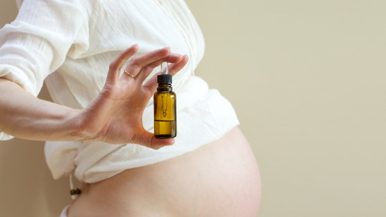 Pregnant woman holding a bottle of essential oils