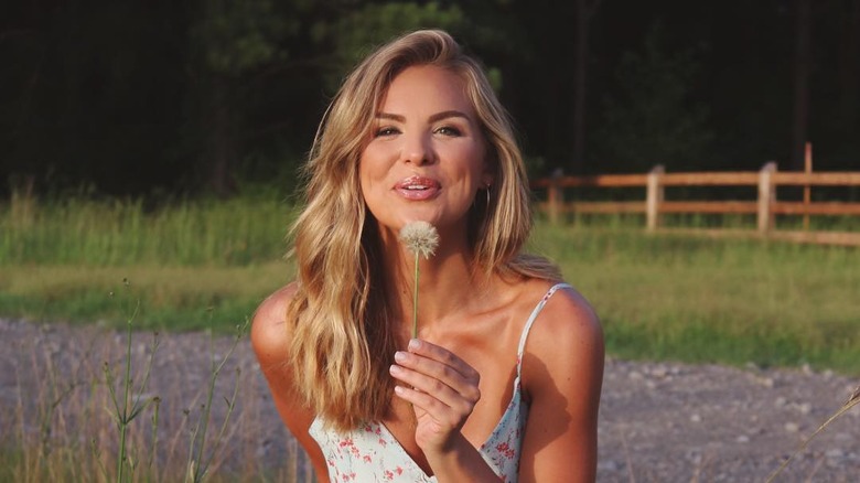 Hannah B blowing on a dandelion