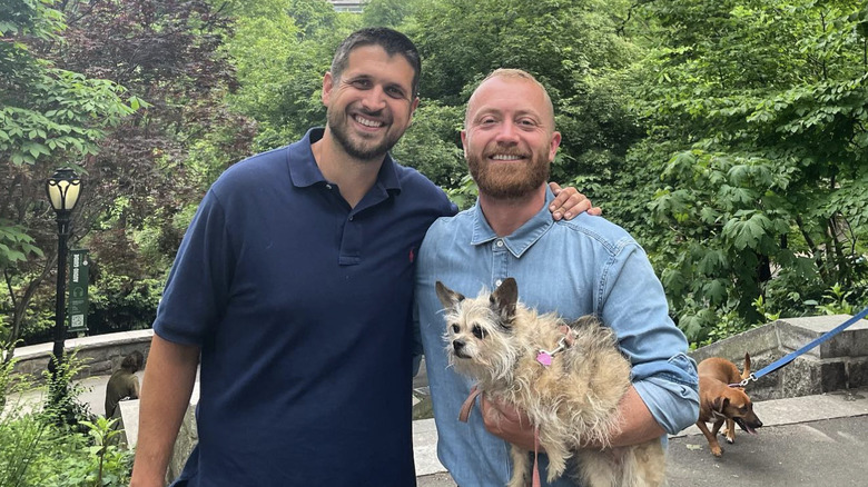 Evan Thomas and Keith Bynum holding dog in park