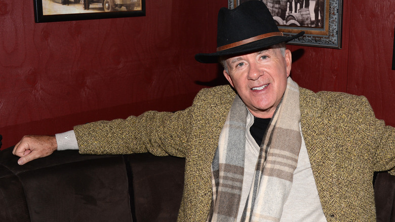 Alan Thicke sitting in a booth wearing a scarf and hat.