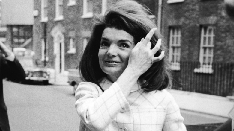 Jackie Kennedy Onassis brushing hair off of her face
