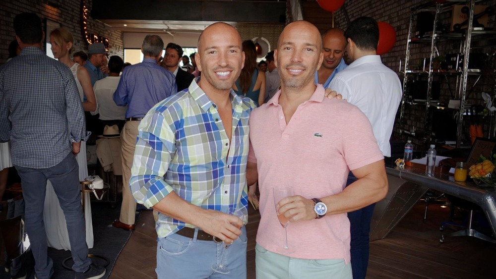 Jason and Brett Oppenheim holding drinks and smiling 