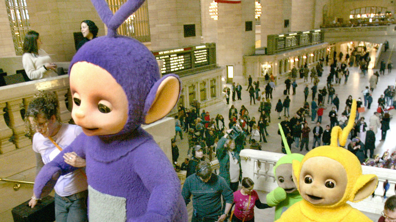 tall Teletubbies being escorted up a staircase