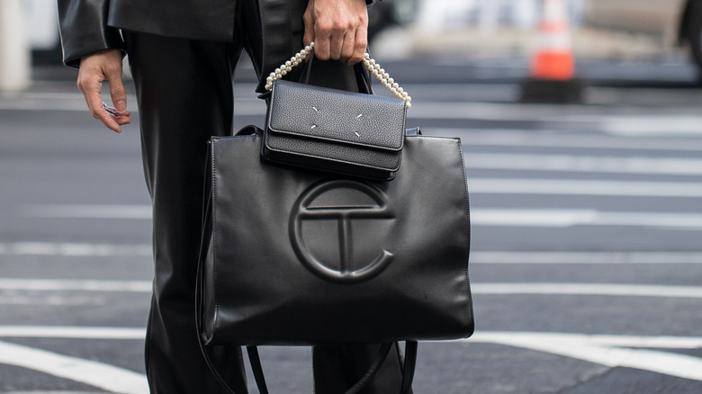 Person in a leather outfit holding a telfar bag