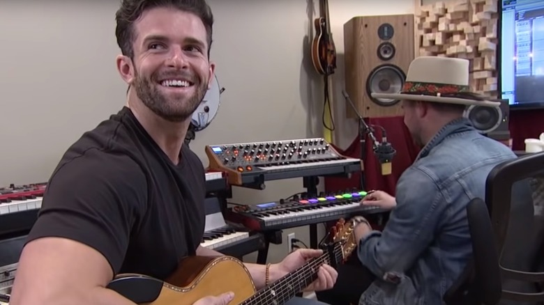 The Bachelorette's Jed Wyatt playing guitar and smiling