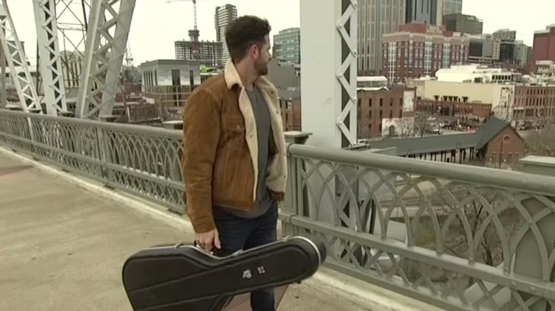 Jed Wyatt walking with his guitar in Nashville for The Bachelorette