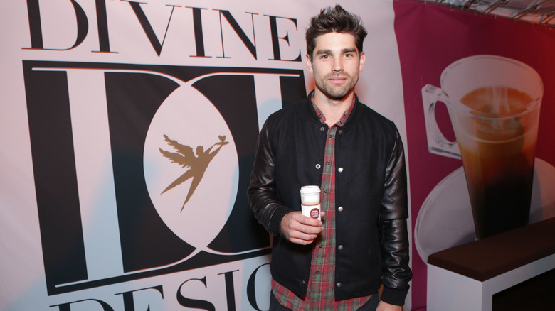 Justin Gaston holding a cup of coffee he is promoting