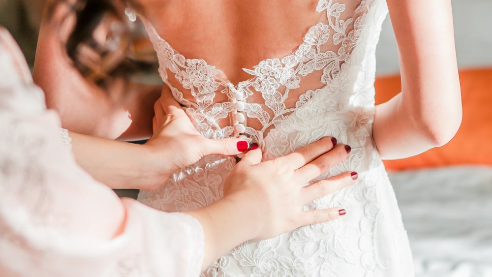 maid of honor helping bride dress