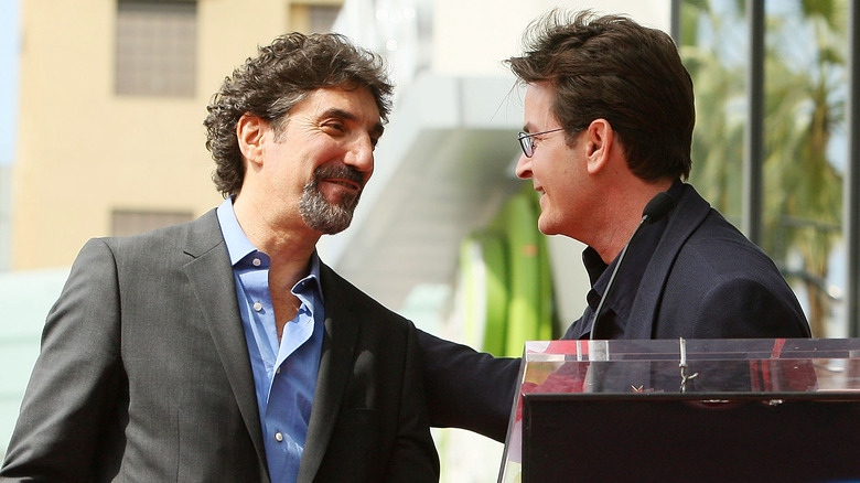 Chuck Lorre and Charlie Sheen smiling at each other