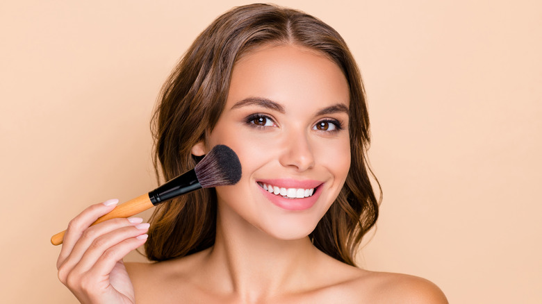 Woman holding a foundation brush to face