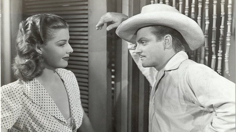 man leaning in door frame in old movie