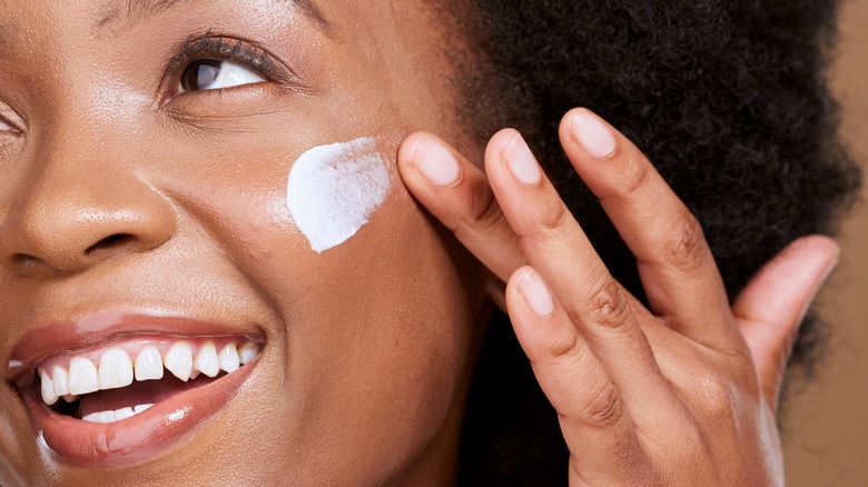 Woman applying cream on face