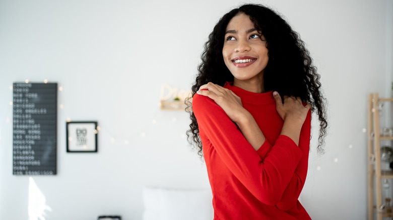 Happy woman holding her shoulders