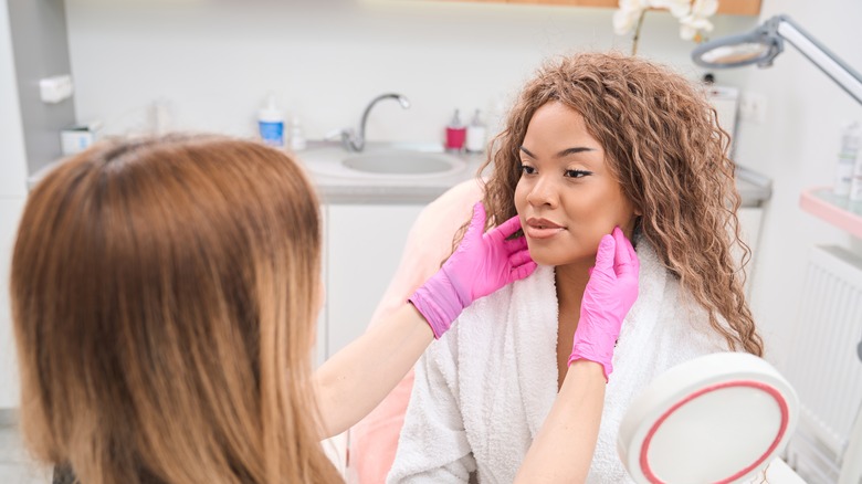 Beautician assessing woman's face