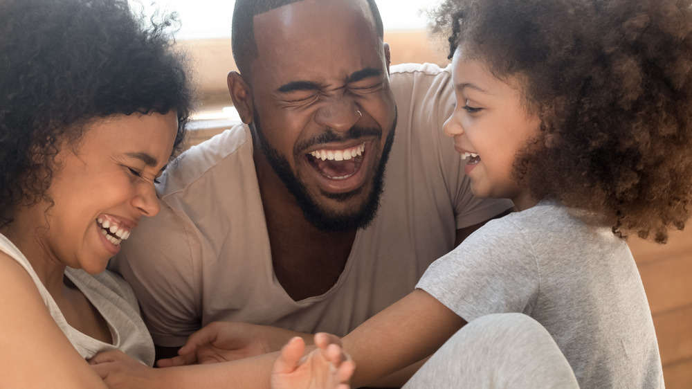 A man, woman, and little girl laughing