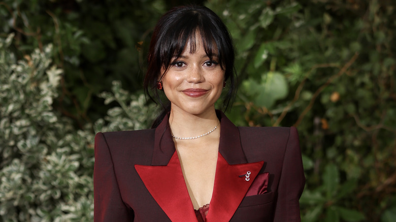 Jenna Ortega smiling in a red blazer