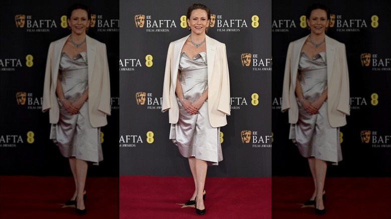 Anna Higgs posing in a white dress and coat at the 2025 BAFTA Awards