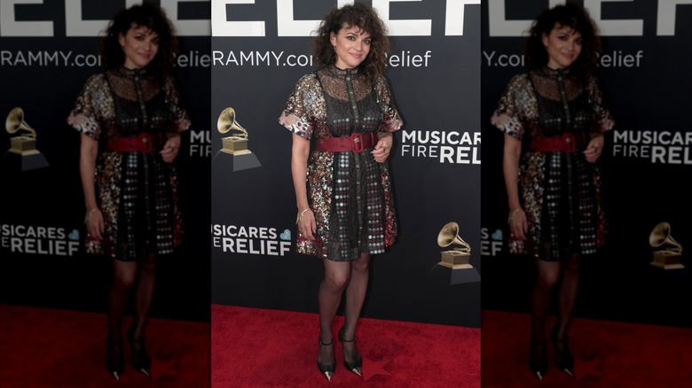 Norah Jones posing in black dress with red belt