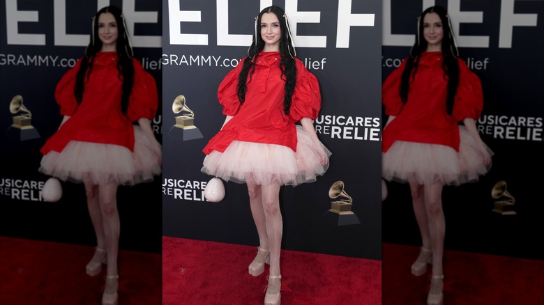 Poppy posing on the red carpet in red coat over tutu