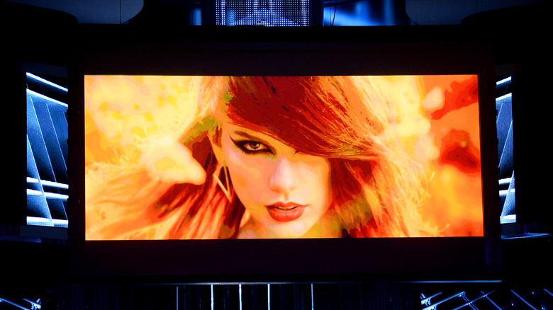 Taylor Swift in a red wig on a jumbotron