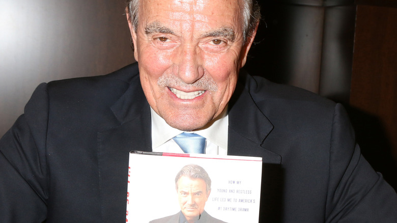 Eric Braeden holding his book and smiling