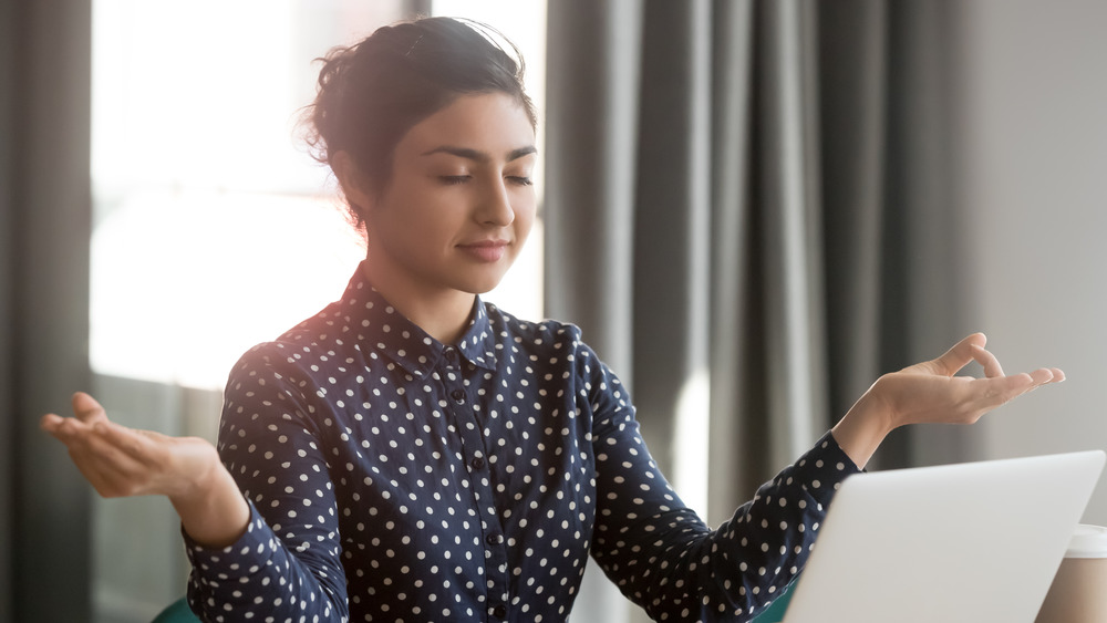 Woman in meditative pose at laptop