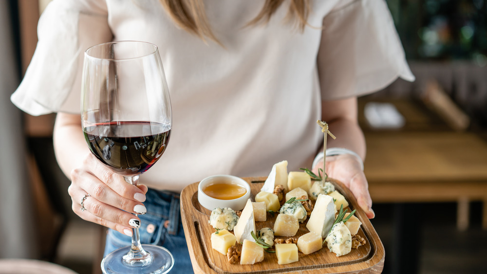 Woman with blonde hair holding glass of wine and charcuterie board