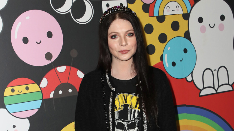 Michelle Trachtenberg posing against a colorful wall 