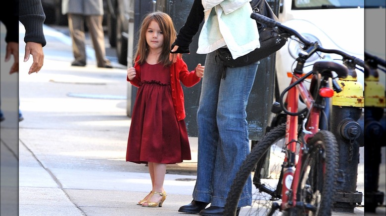 Toddler Suri Cruise wearing a red dress and gold heels