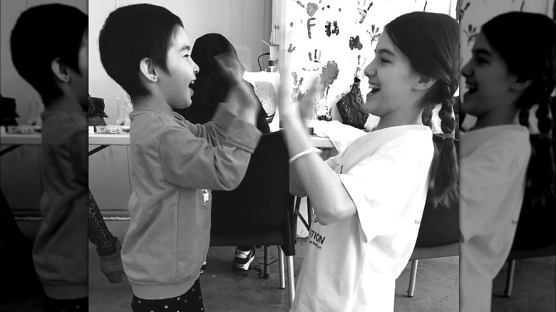 Suri Cruise as a child giving a high five to a smaller child 