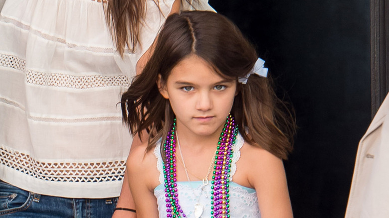 Child Suri Cruise wearing beaded necklaces and a bow 