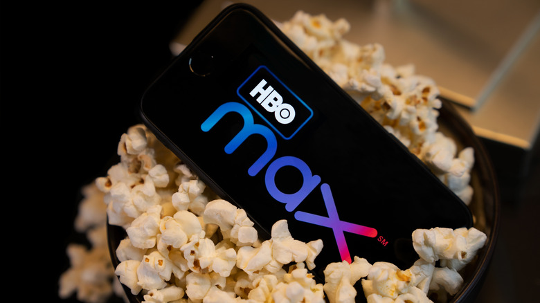 HBO max logo on a phone screen surrounded by popcorn