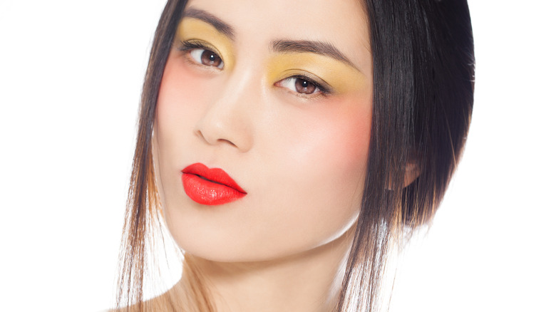 Woman with yellow eyeshadow, orange blush and red-orange lipstick