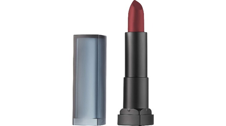 tube of dark red lipstick next to lipstick cap