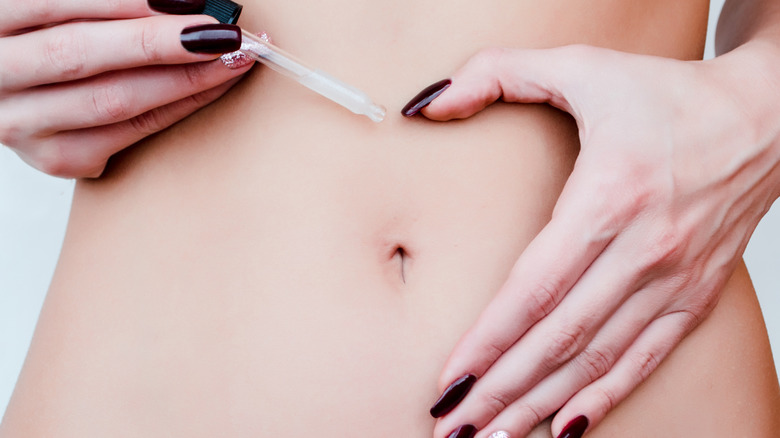 Woman placing essential oils on her stomach