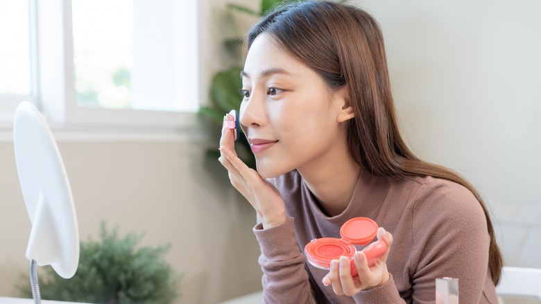 woman applying blush to her cheeks