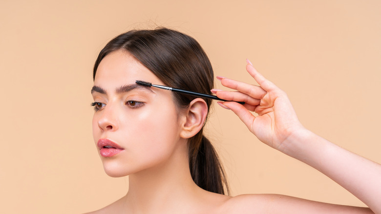 Woman brushing her eyebrows